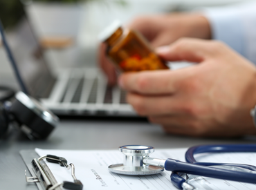 View of a doctor's hands holding a pill bottle