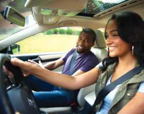 Teenager driving a car with a passenger.