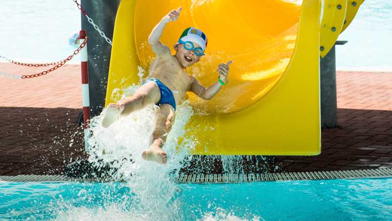 kid sliding into pool on water slide