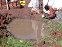 A brickmaker near the burrow pit resulting from his work.