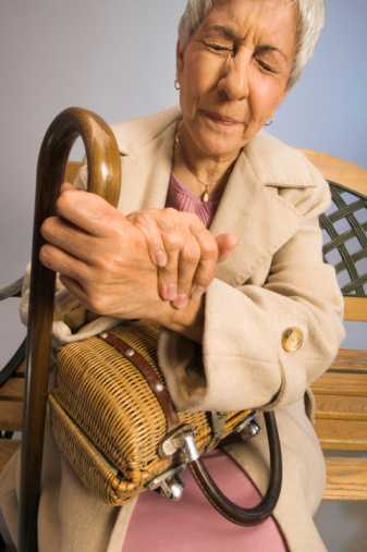 Elderly woman holding her writst, in pain