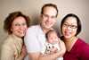 Three adults wearing glasses holding an infant