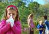 Photo: Child blowing her nose with children playing in the background