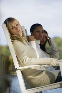 Three woman sitting on chairs on a porch