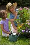 A girl helps a woman plant flowers