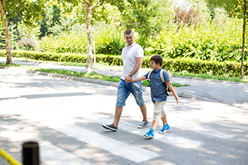 Boy crossing the street with his father