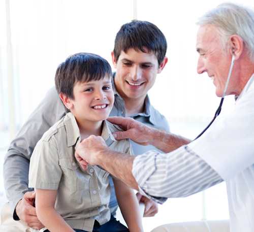 Doctor examining boy with his dad