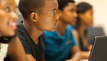 Boy sitting in classroom with a laptop