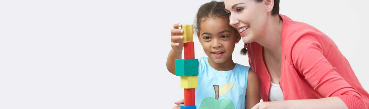 Teacher beside a little girl playing with blocks