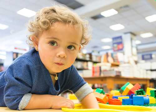 Toddler crawling on the floor with blocks beside her