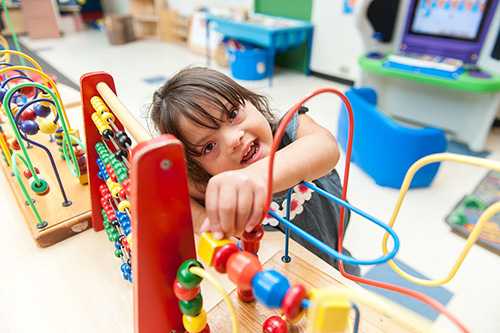 Young child playing with a wooden slider toy