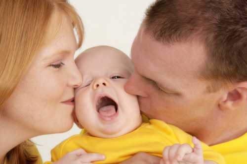 Mom and dad kissing there baby