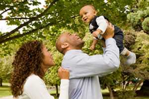 Dad and mom walking with infant. Dad tossing infant into the air.