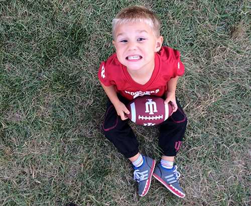 Jefferson sitting in the grass holding a football.