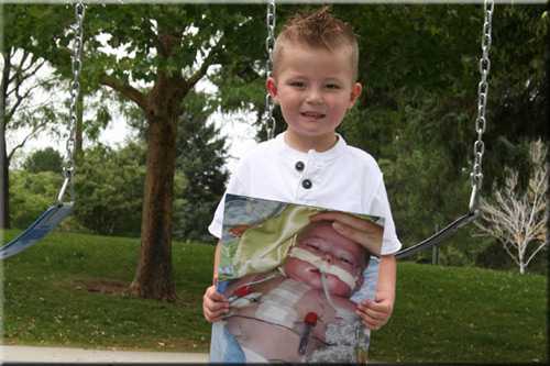 Teagan holding a picutre of himself in the hospital