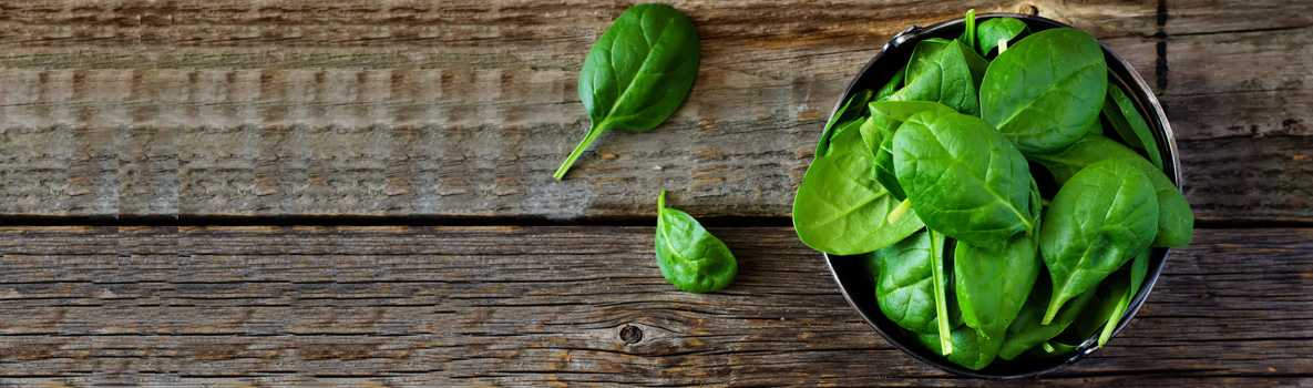 Bowl of spinach on a rustic wooden table