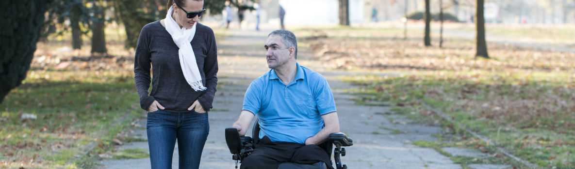 Photo of man in electric wheelchair with woman walking beside him