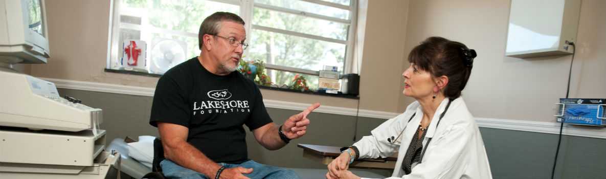 Photo of Jerry in a wheelchair, talking with his doctor