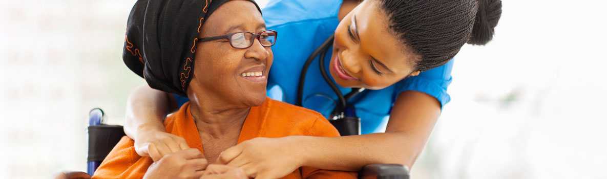 A nurse hugging a woman in a wheelchair