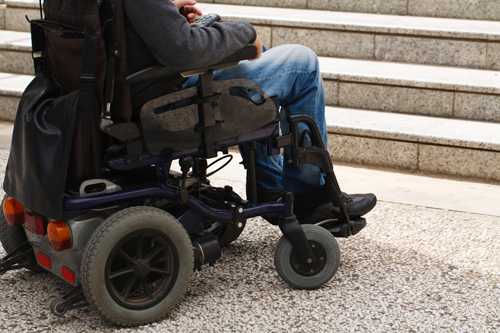 Person in a wheelchair at the bottom of steps.