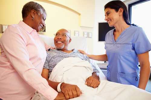 Nurse talking with elderly couple in hospital