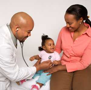 Mother holding her baby girl while the doctor listens to the baby's heart.