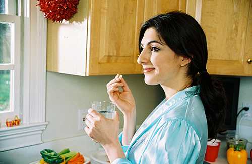 Woman taking folic acid with water.