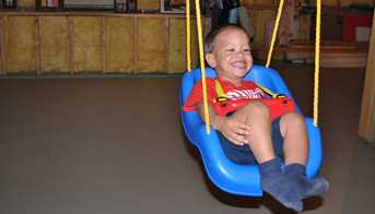 Boy siwning on a swing in the basement