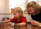 Mom playing at a table with her daughter.