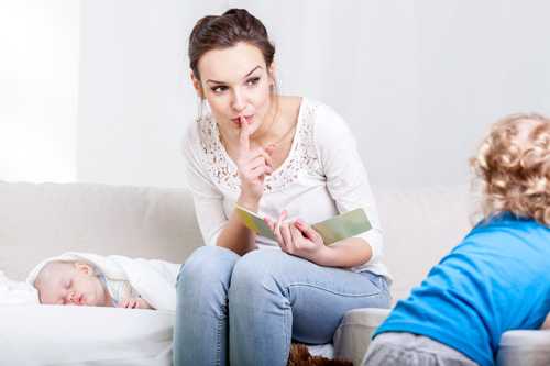 Mom holding finger over mouth telling toddler to be quiet.