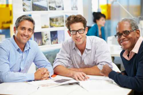 Photo of diverse men sitting at a table smiling