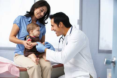 Doctor examinando niño en el regazo de su madre.