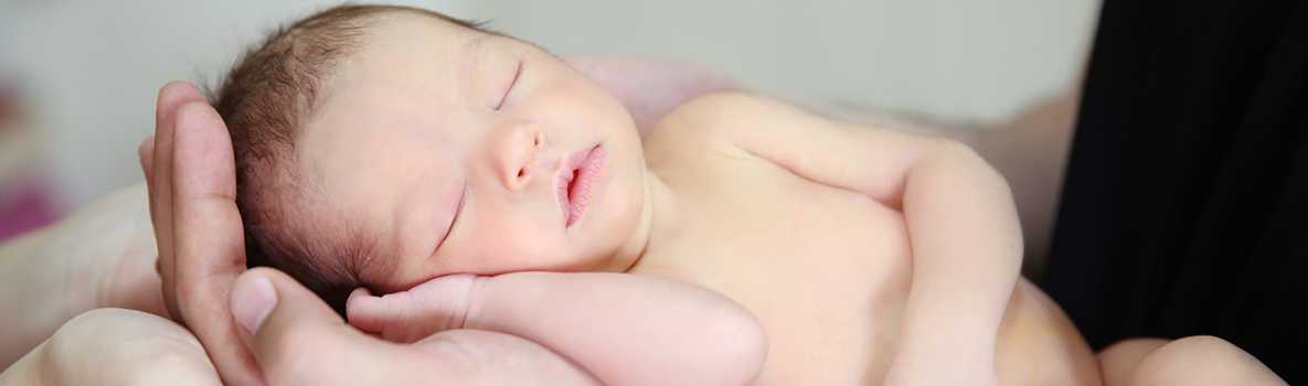 Hands of father and mother holding newborn baby