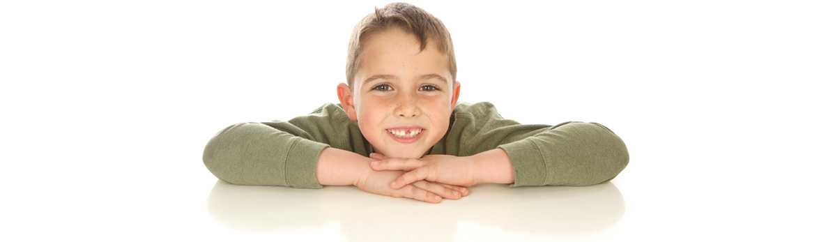 Boy with missing tooth laying head on hands