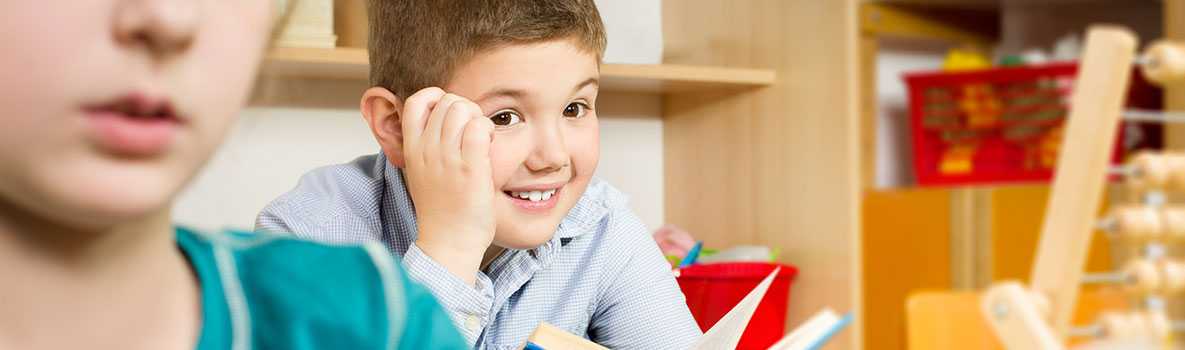 A school age boy reading in class