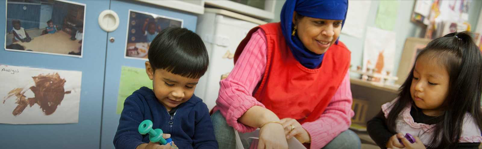 An early care provider plays with two children.