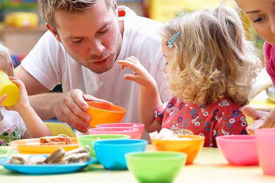 A childcare provider helps a child pick a snack.