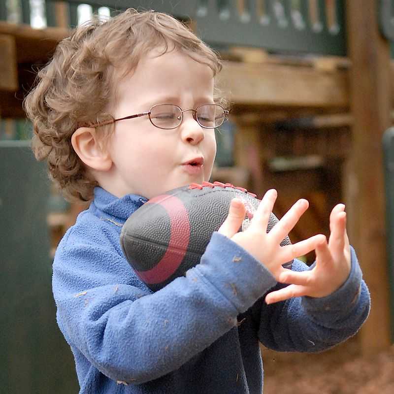 A boy catches a football outside on the playground.