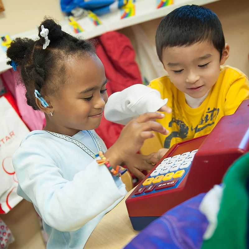 Two children play together with a cash register