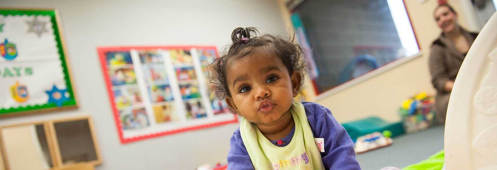 A toddler crawls across the floor at daycare.