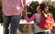 School-aged girl holds a stop sign, acting as a crossing guard for young boys and girls crossing the street on their way to school