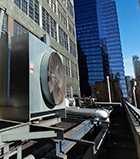 Photo of an outdoor HVAC air conditioner unit located on a high-floor porch of a New York skyscraper.