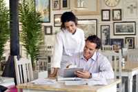 Photo of 2 restaurant employees reviewing records.