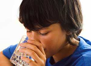 Photo of a boy drinking water from a glass.