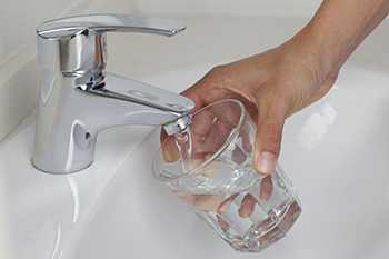 	hand filling a glass under a running faucet