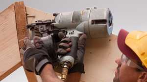 man using a nail gun on construction site