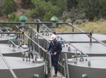 	Worker preparing to gauge oil production tanks.