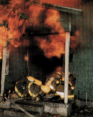 Fire fighters wearing self-contained breathing apparatus (SCBAs) and other protective gear at the scene of a fire