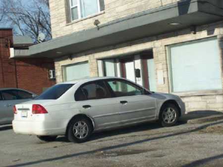 Photograph of shop showing car and building.