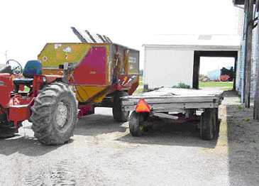 Hay wagon used in process of loading feed grinder-mixer. Note: hay wagon is normally on the other side of the machine for loading purposes.